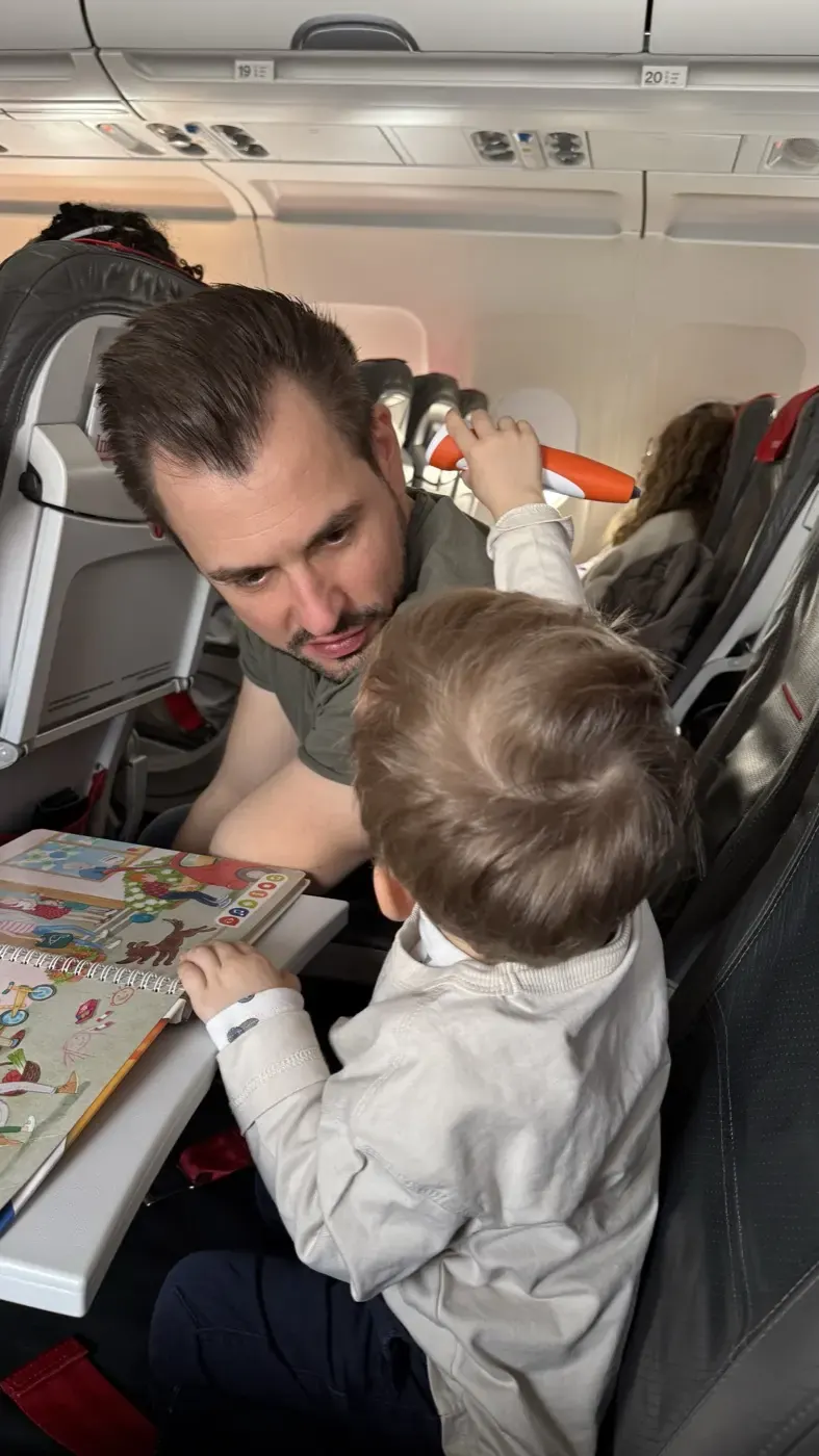 Vater und Kind malen gemeinsam am Klapptisch im Flugzeug