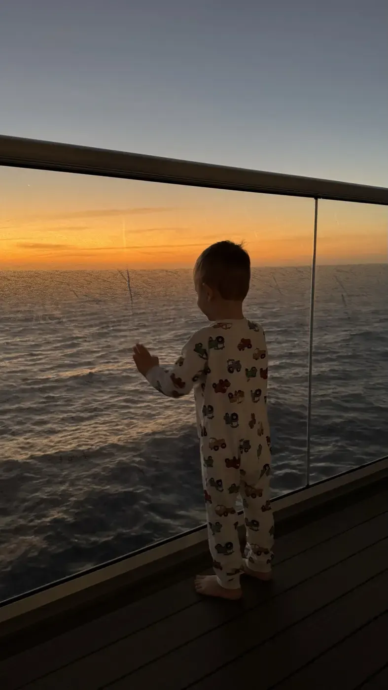 Kind schaut an der Reling in den Sonnenuntergang
